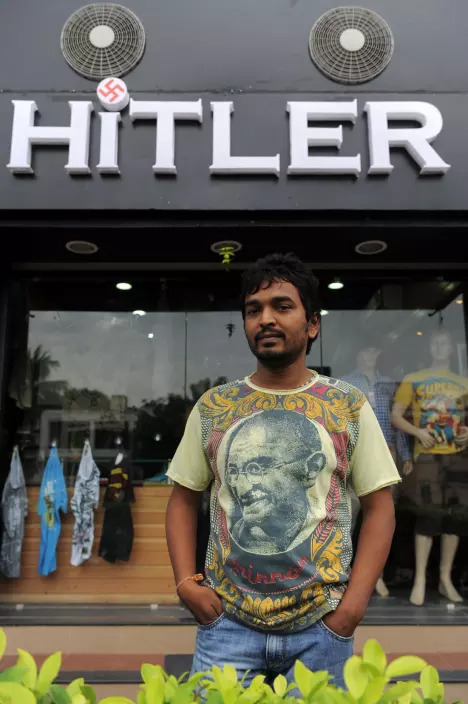 Rajesh Shah, one of the Indian owners of the Hitler clothing store poses in a t-shirt adorned with an image of Mahatma Gandhi, in front of his shop in Ahmedabad, August 28, 2012.AFP PHOTO/Sam PANTHAKY
